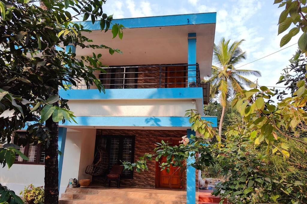 une maison bleue et blanche avec un palmier dans l'établissement Wanderers Stays, à Mangalore