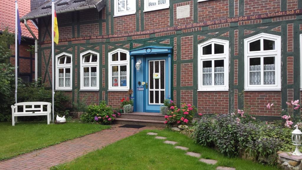 uma casa de tijolos com uma porta azul e janelas brancas em Landhotel Sonnenhof im Wendland em Clenze