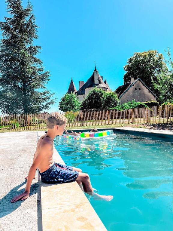 un jeune garçon assis au bord d'une piscine dans l'établissement La Grange de Verseilles, à Saint-Étienne-de-Vicq