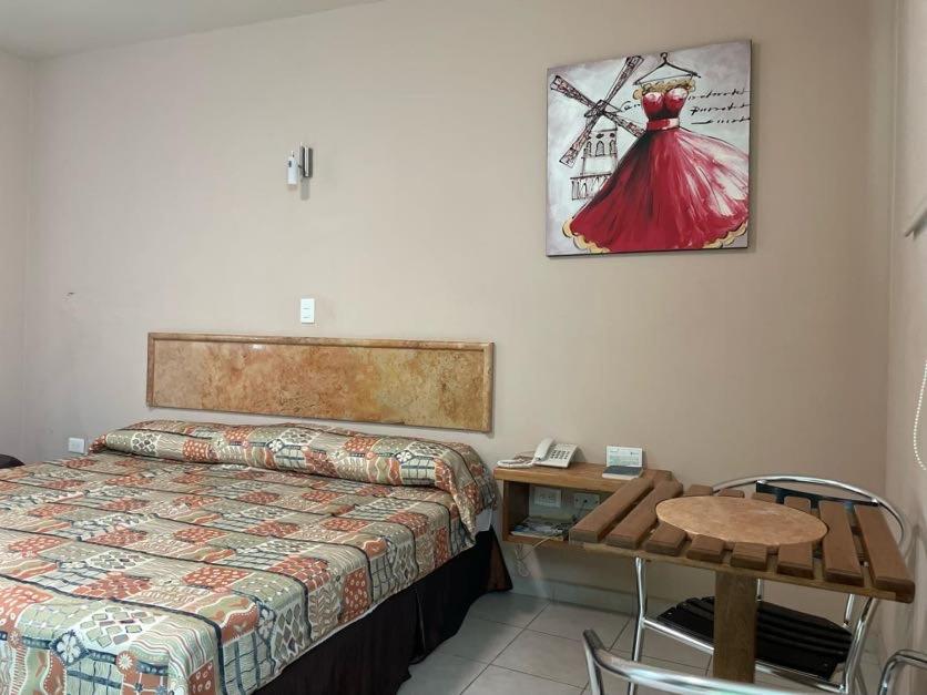 a bedroom with a bed and a table and a picture on the wall at Hotel Santo Domingo Express in Villahermosa