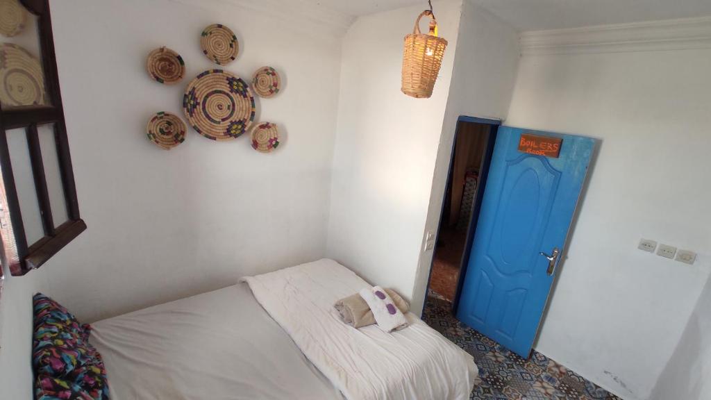 a small room with a bed and a blue door at EL Faro Surfstay in Tamri