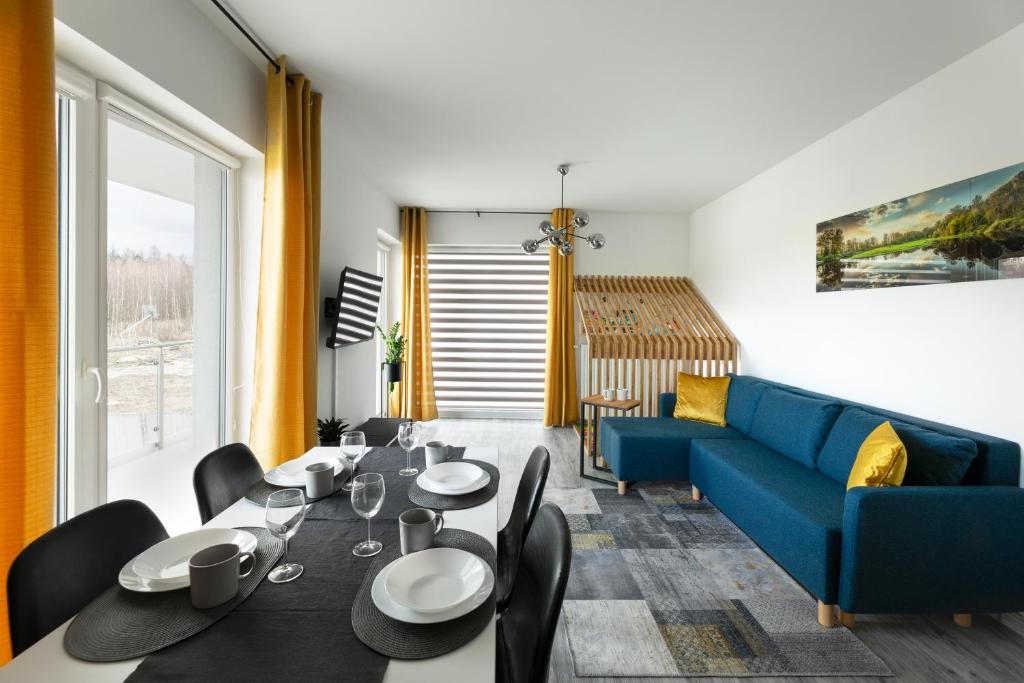 un soggiorno con tavolo e divano blu di Apartament Rodzinny - Lamelowy Domek a Kudowa-Zdrój