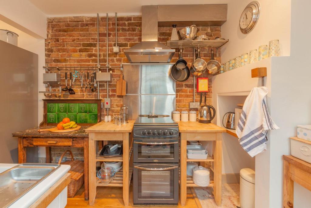 a kitchen with a stove and a brick wall at The Roost in Whitstable