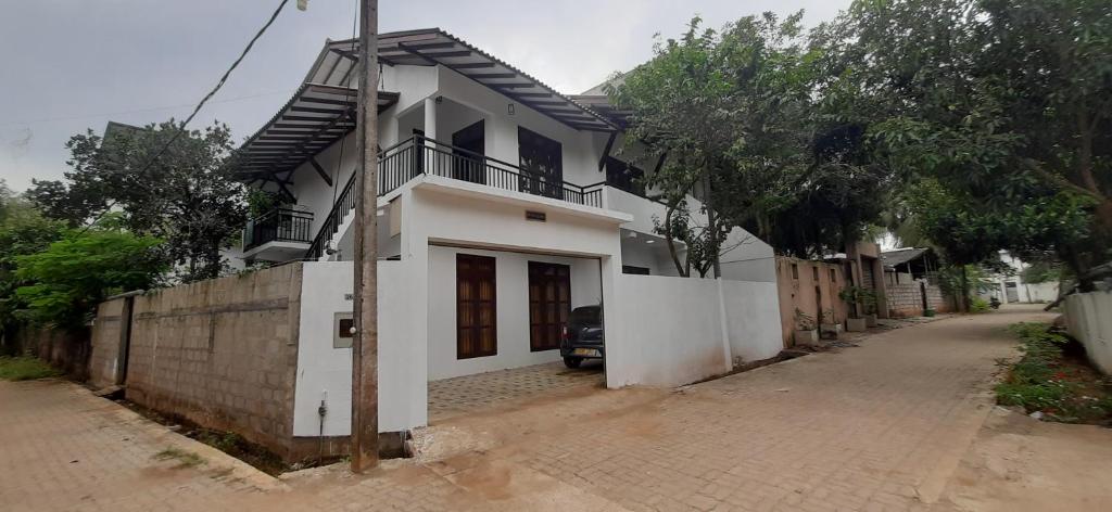 Casa blanca con balcón en una calle en Family Time Holiday Home, en Anuradhapura