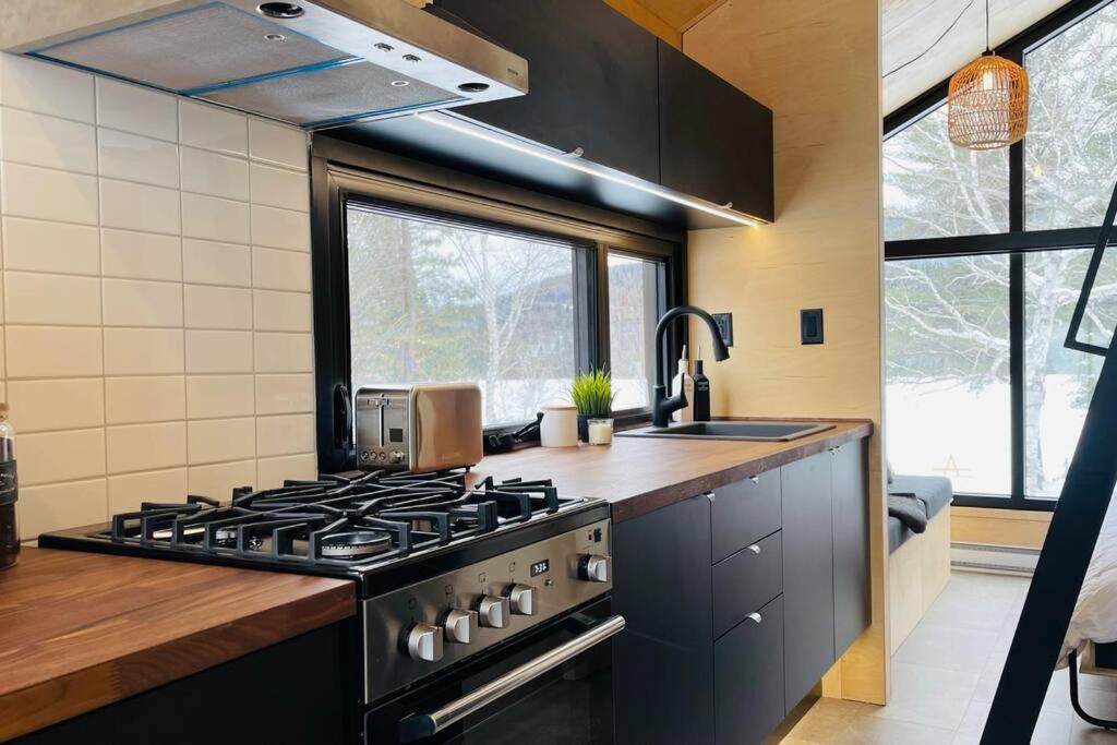 a kitchen with a black stove and a sink at Micro maison le Nordik in Saint Zenon