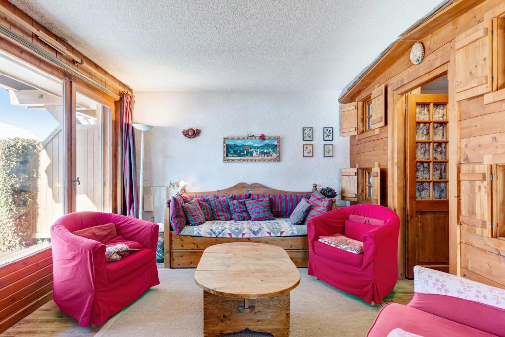 a living room with two pink chairs and a table at Charming flat with garden nearby the slopes - Welkeys in Megève