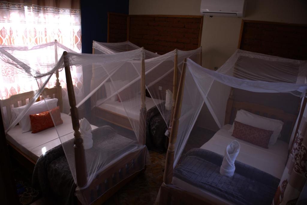 un grupo de 4 camas con dosel en una habitación en MANTIS LODGE & CAMPING SITE, en Morogoro
