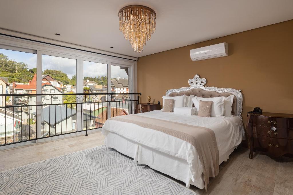 a bedroom with a bed and a balcony with a chandelier at Hotel Fioreze Centro in Gramado