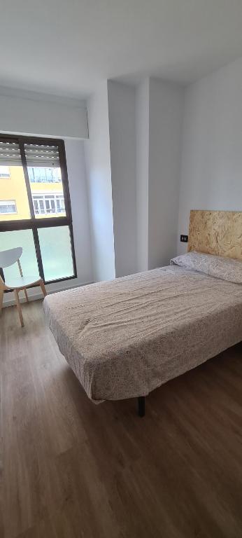 a bedroom with a bed and a chair in it at Lovely apparment in fornt of the port of Gandia in Los Mártires