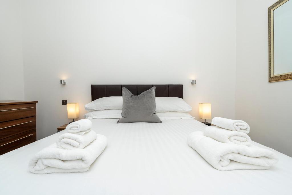 a bedroom with a white bed with towels on it at Howburn Residence Serviced Apartments - 1,2& 3 Bedroom Apartments in Aberdeen
