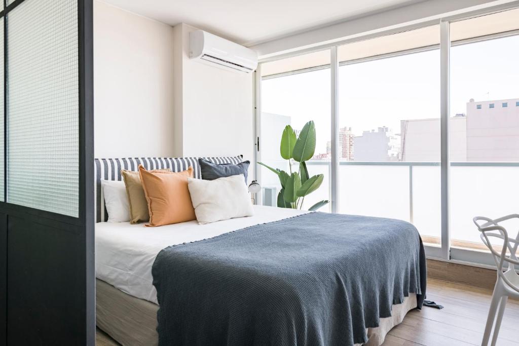 a bedroom with a bed with pillows and a plant at Top Rentals Belgrano in Buenos Aires