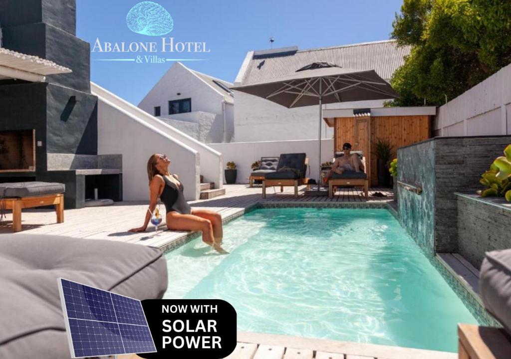 a woman sitting on the edge of a swimming pool at Abalone Hotel & Villa's in Paternoster