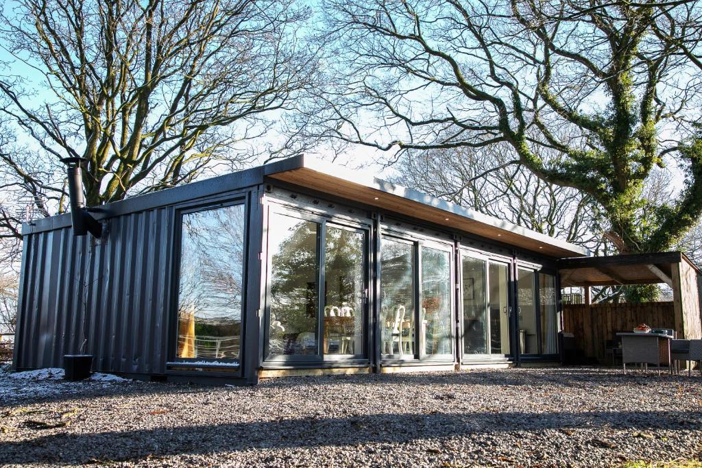 a small black house with glass windows and a tree at Bird House - Sleep with the Owls! in Carlisle