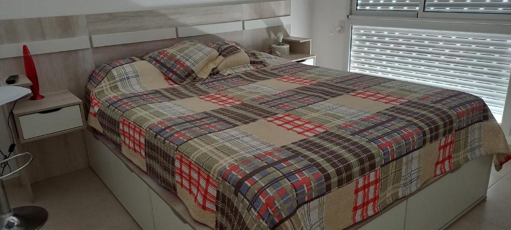 a bedroom with a bed with a plaid blanket on it at Departamento126 in Junín