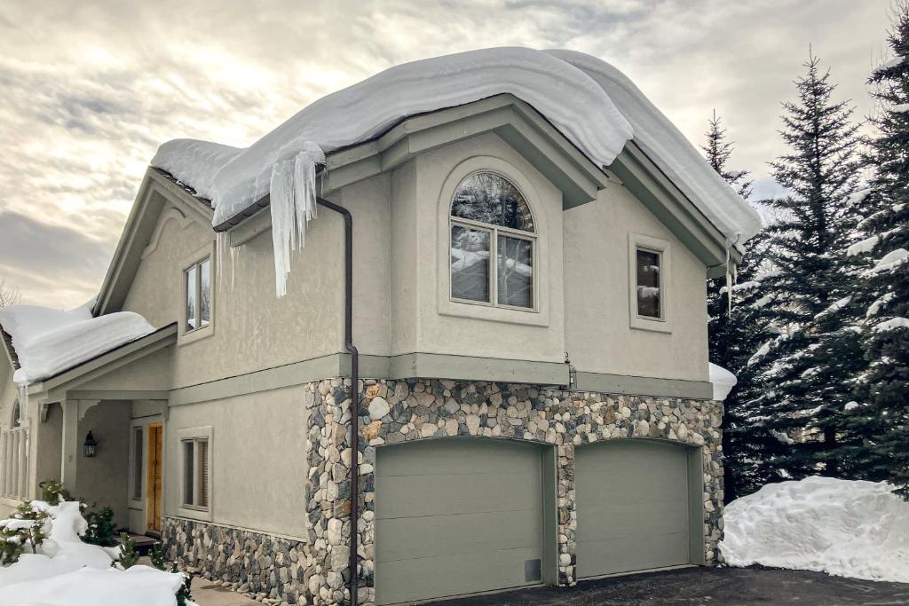 una casa con techo cubierto de nieve y dos puertas de garaje en Leisure in Vail, en Vail