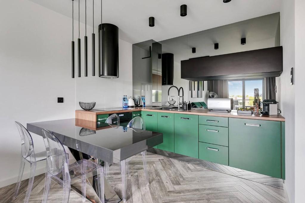 a kitchen with green cabinets and a table with chairs at Nadmorze by Q4Apartments in Gdańsk