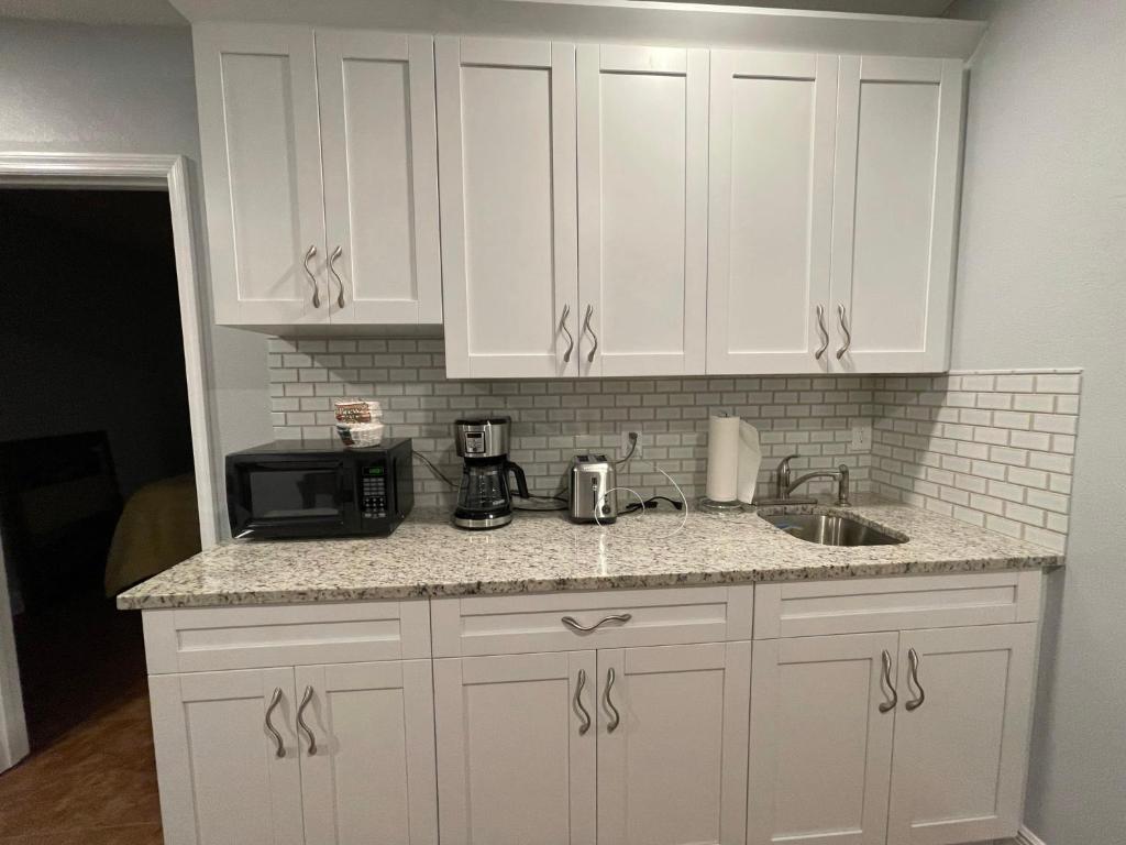 a kitchen with white cabinets and a sink and a microwave at Twelve Oaks modern independent apartment in Tampa