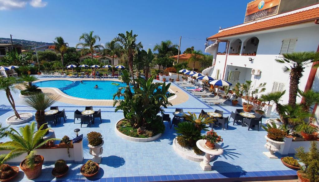 un complejo con piscina, mesas y sillas en Hotel Damanse, en Santa Domenica