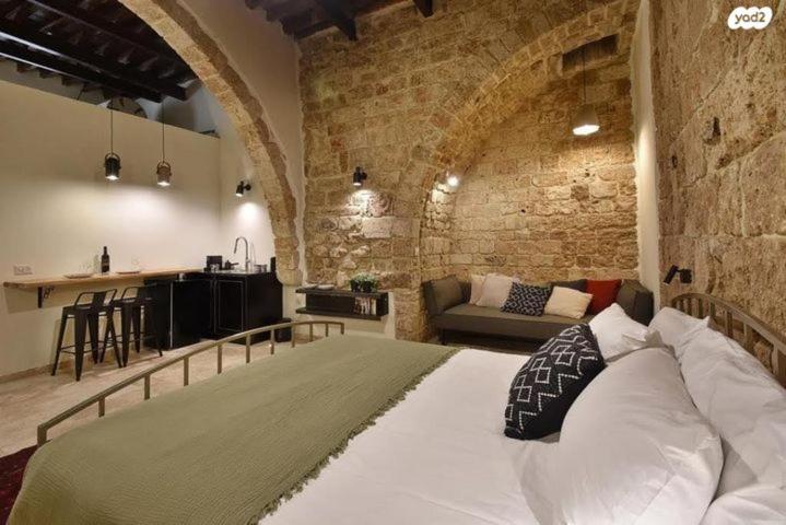 1 dormitorio con 1 cama grande en una pared de ladrillo en Napoleon suites en ‘Akko