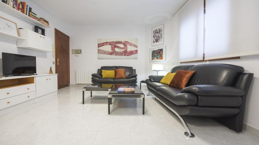 a living room with two black leather chairs and a tv at Casa Recogidas - Apartamentos Aloha Toledo in Toledo