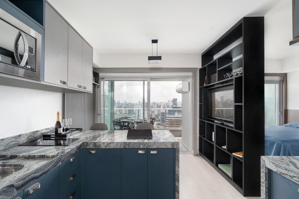 una cocina con armarios azules y una gran ventana en River One 2303 - Luxury Studio, en São Paulo