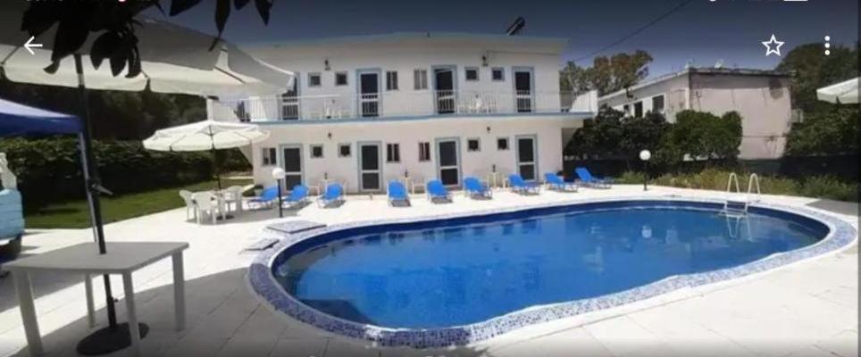 a swimming pool in front of a house at Rose Apartments Mesonghi in Moraitika