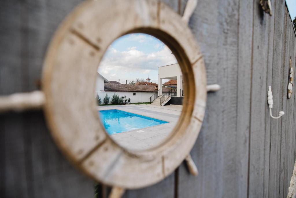 a mirror on a wooden fence with a swimming pool at Pensiunea Magnesia (4 margarete****) in Sânâteşti