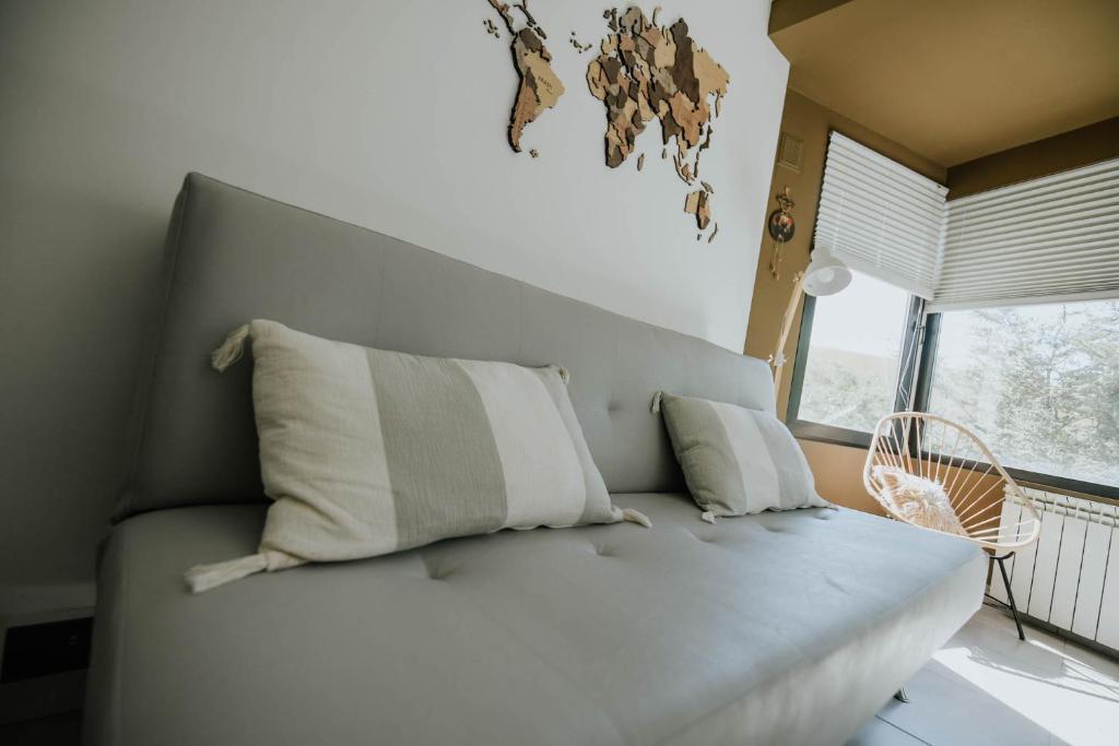 a white couch with two pillows in a room with a window at Mystic Mountains - Bienvenido/Welcome. Check in & Chill in Ushuaia