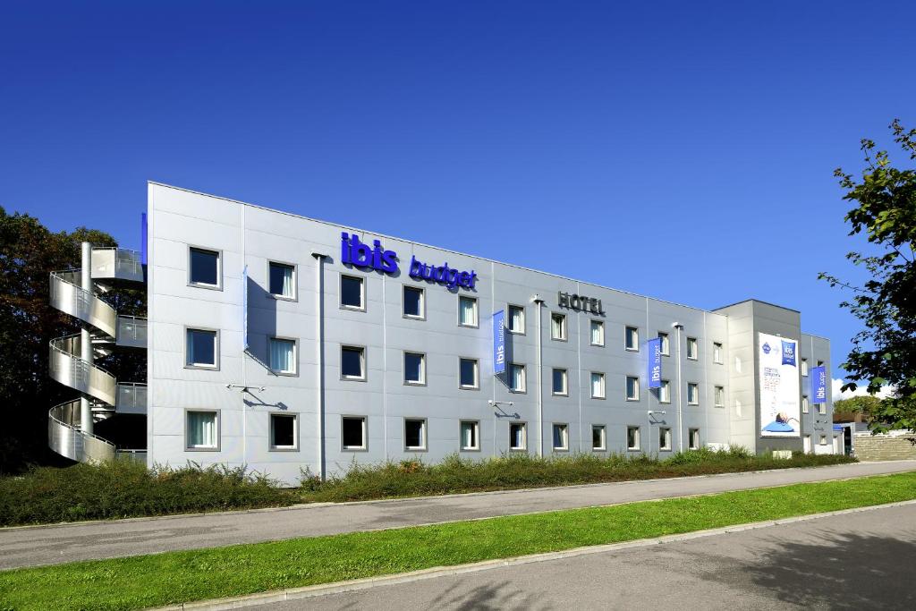 a large white building with a blue hotel sign on it at ibis budget Aachen Raeren Grenze in Raeren