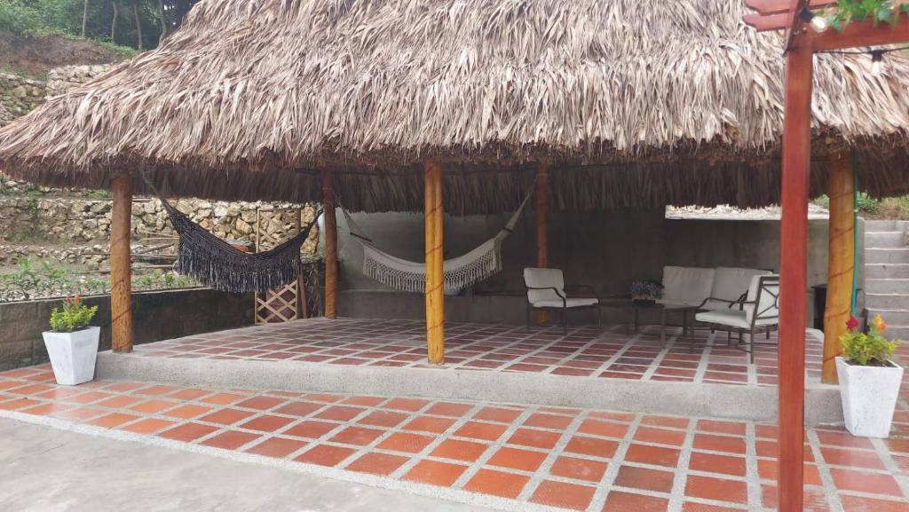 a hut with chairs and a hammock in it at La Casa de Tita _ Usiacuri in Usiacurí