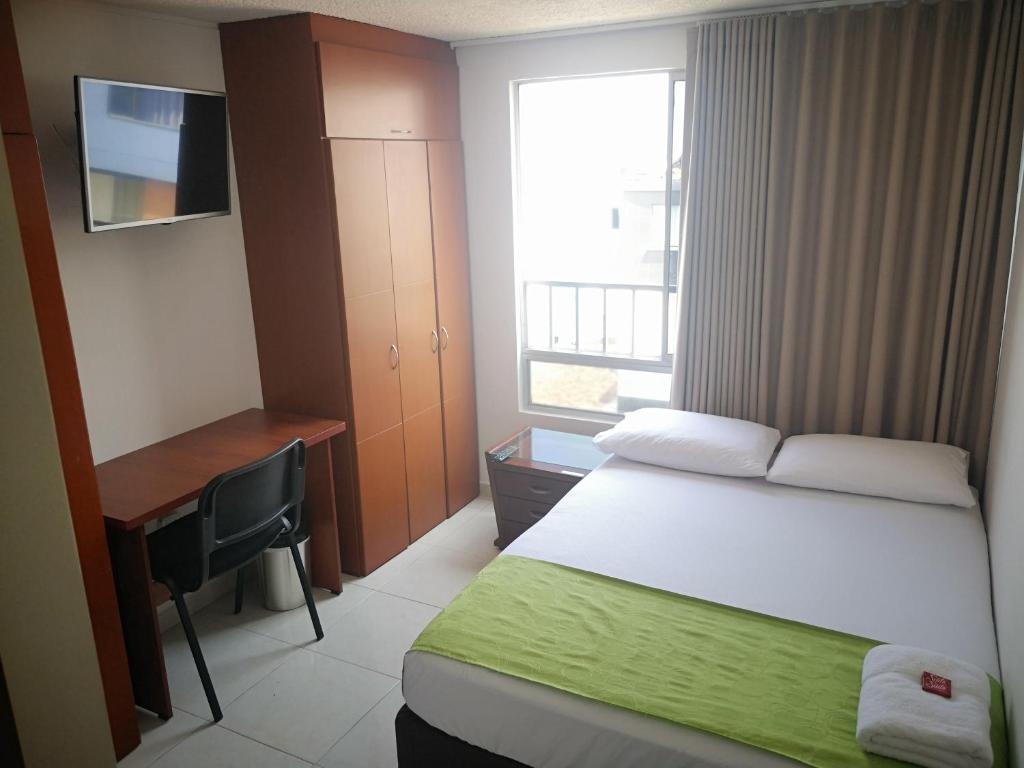 een slaapkamer met een bed, een bureau en een raam bij Habitar de Asis in Bucaramanga