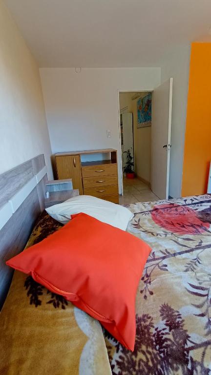 1 dormitorio con 2 camas y almohada roja en Casa Jardín en Necochea