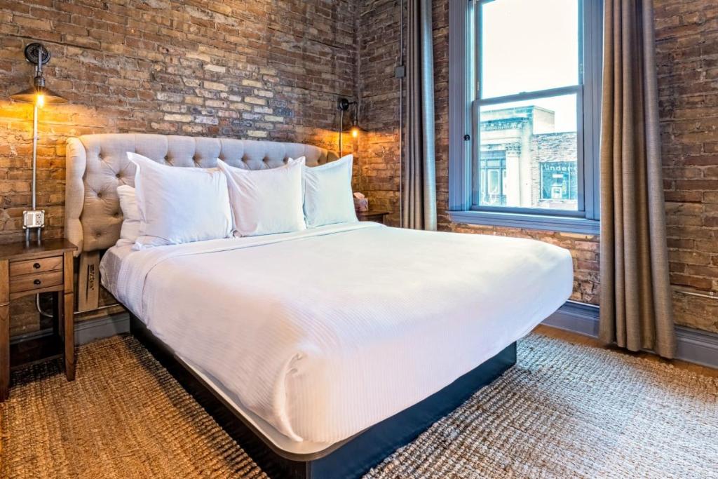 a large bed in a room with a brick wall at Hip Urban Loft - Small Town Charm - 124 LOFTS #1 in West Dundee