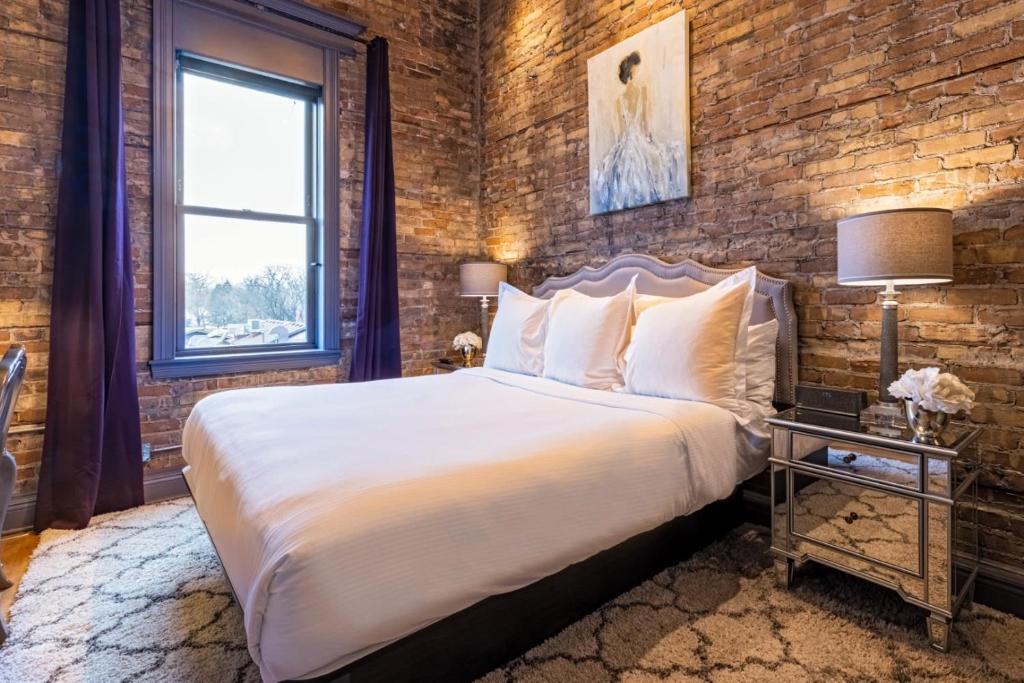 a bedroom with a large bed and a brick wall at Hip Urban Loft - Small Town Charm -124 LOFTS #3 in West Dundee