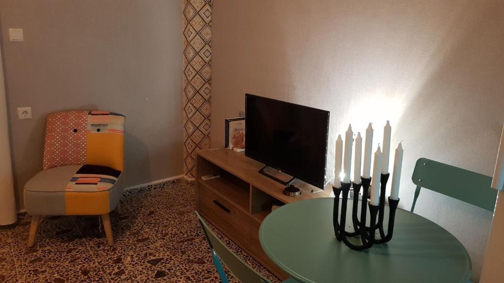 a living room with a table with a television and a chair at Isa apartamento in Hersonissos