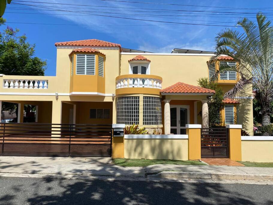 a yellow house with a fence in front of it at Villa Del Carmen Family Vacation Home in Isabela
