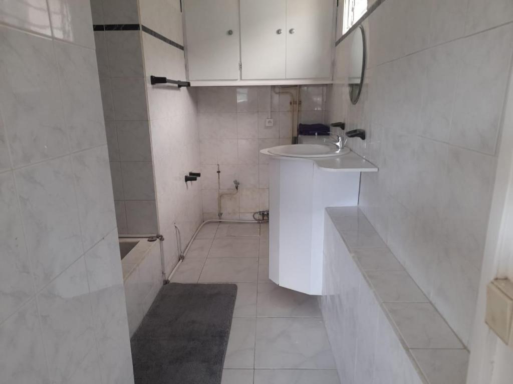 a white bathroom with a sink and a mirror at FLEURIE in Gourbeyre