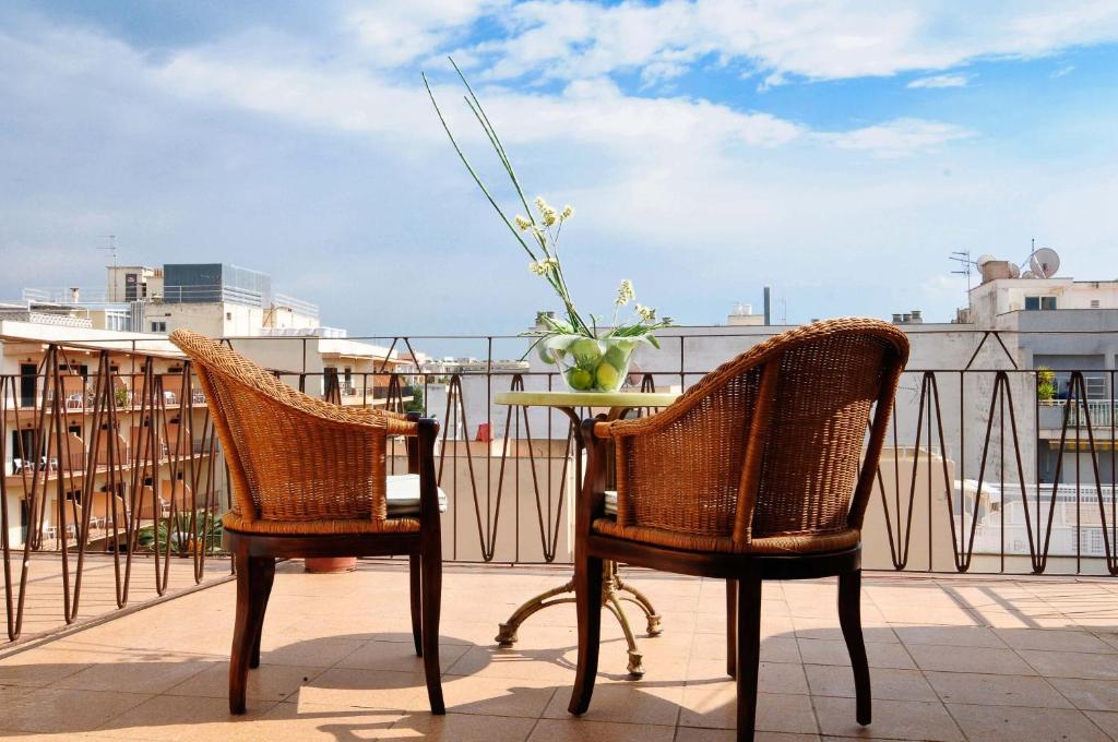 2 stoelen en een tafel met een vaas met bloemen op een balkon bij Hotel Balear in Can Pastilla