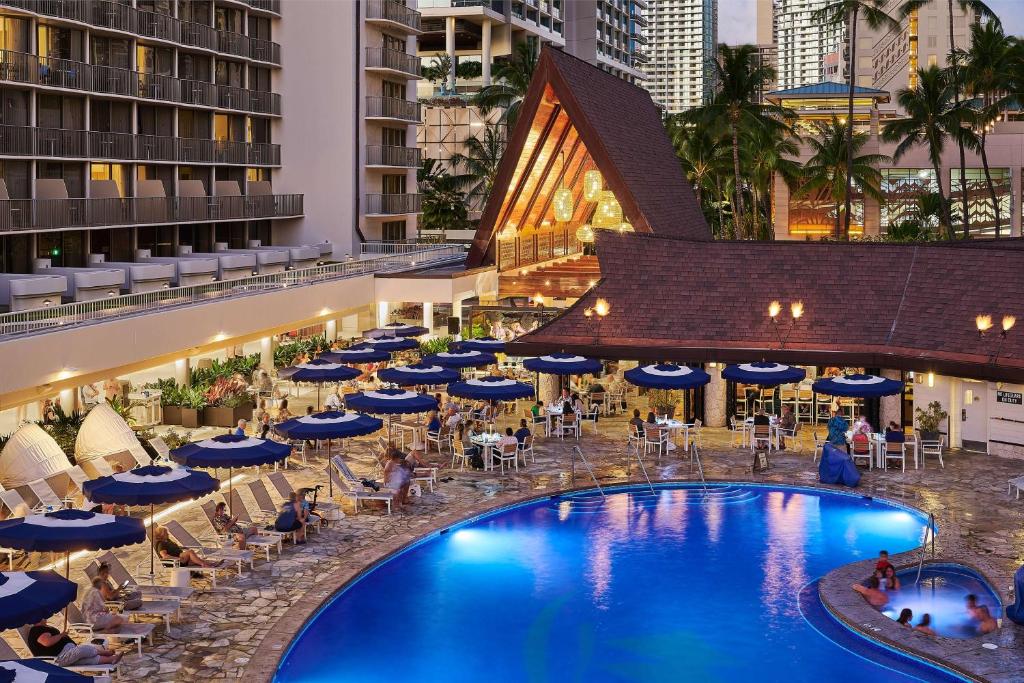 Bild eines Hotelpools mit Stühlen und Sonnenschirmen in der Unterkunft OUTRIGGER Reef Waikiki Beach Resort in Honolulu