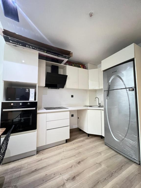 a kitchen with white cabinets and a stainless steel refrigerator at City centre Apartment in Esenyurt