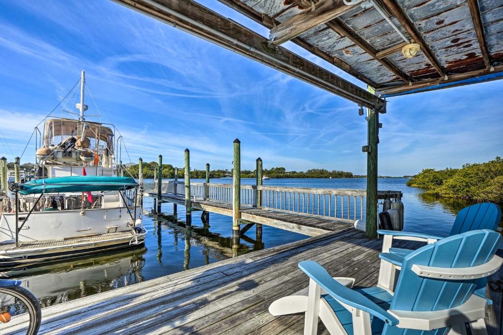a dock with two chairs and a boat on the water at Waterfront Tarpon Springs Vacation Rental! in Tarpon Springs