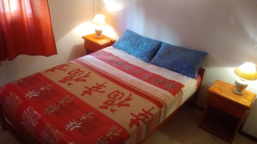 Un pequeño dormitorio con una cama con mantas y almohadas de colores. en Edif. Meridiano XXVII en San Bernardo
