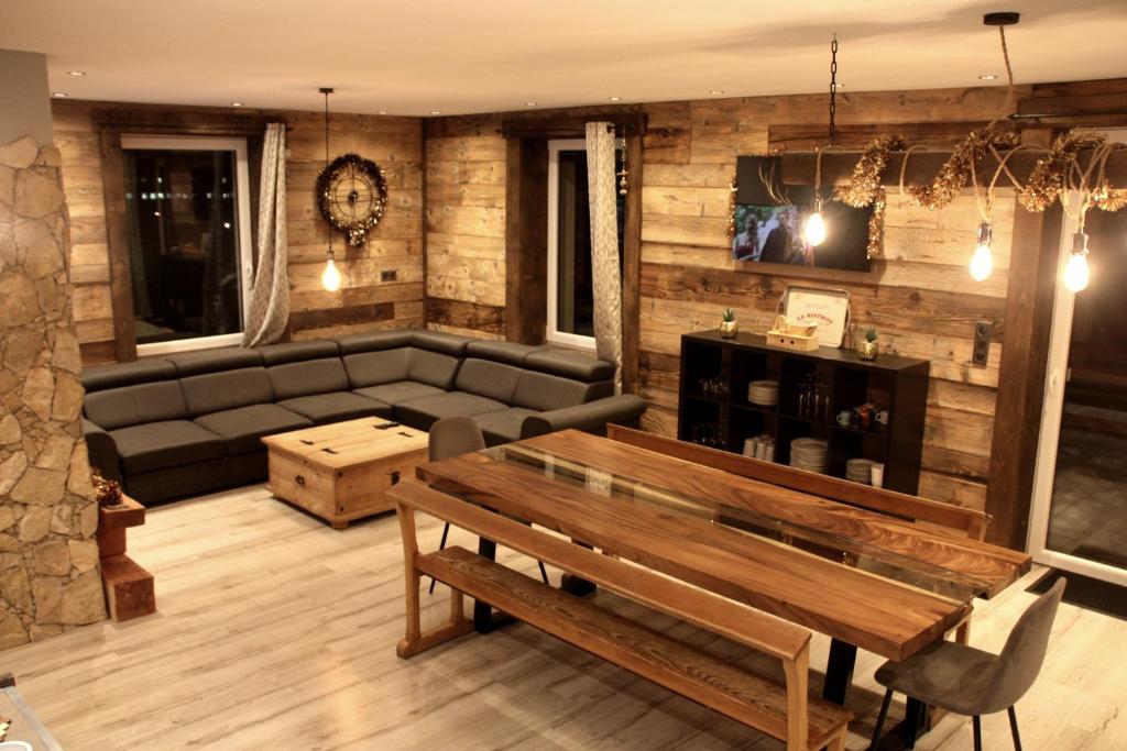 ein Wohnzimmer mit einem Sofa und einem Tisch in der Unterkunft Le joli bois 12 personnes 5/ch spa/sauna Gérardmer in Gérardmer