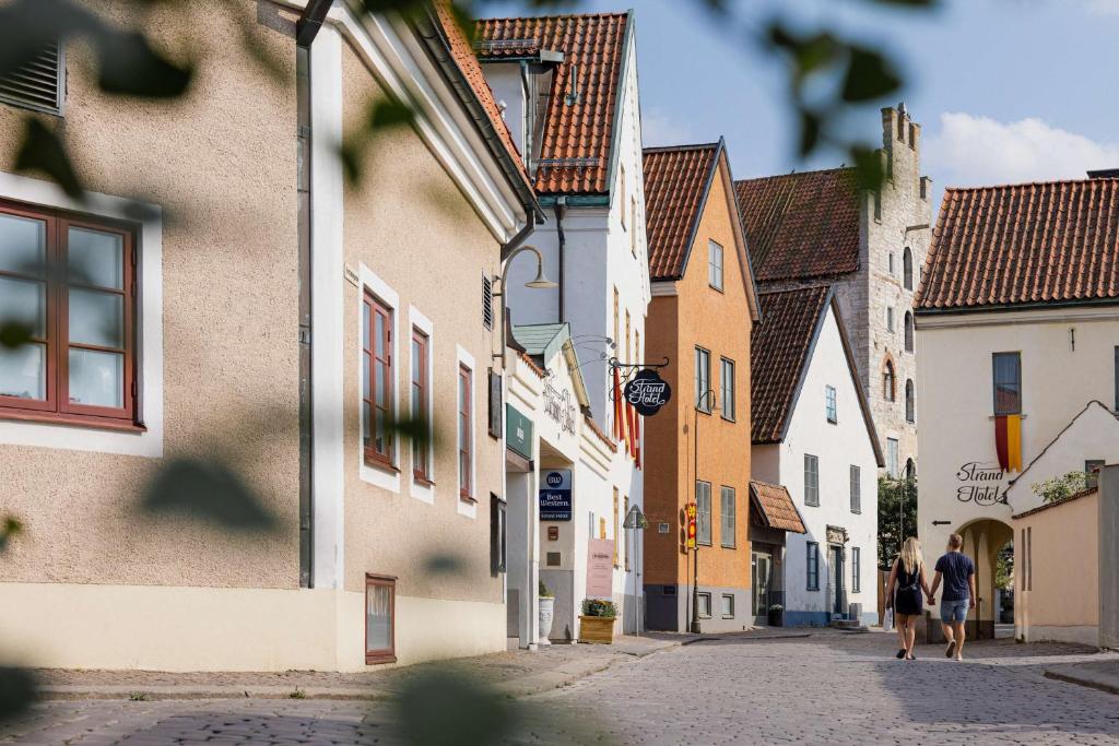 dos personas caminando por una calle en un pueblo en Best Western Strand Hotel en Visby