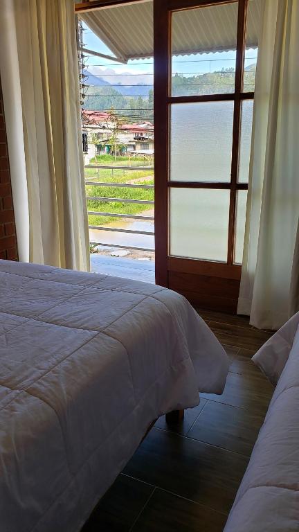 a bedroom with a bed and a large window at Las Yungas Hospedaje in Oxapampa