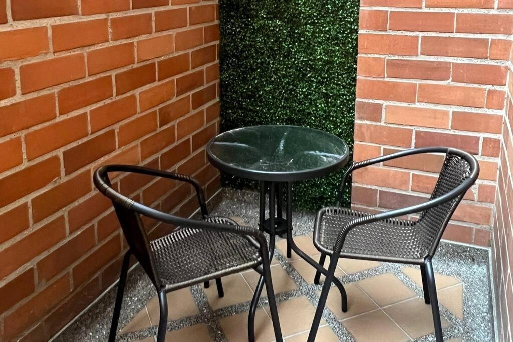 una mesa y dos sillas junto a una pared de ladrillo en Apartamento en Medellín, laureles, en Medellín