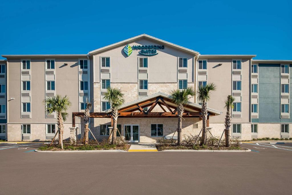 un hôtel avec des palmiers dans un parking dans l'établissement WoodSpring Suites Wesley Chapel-Tampa, à Wesley Chapel