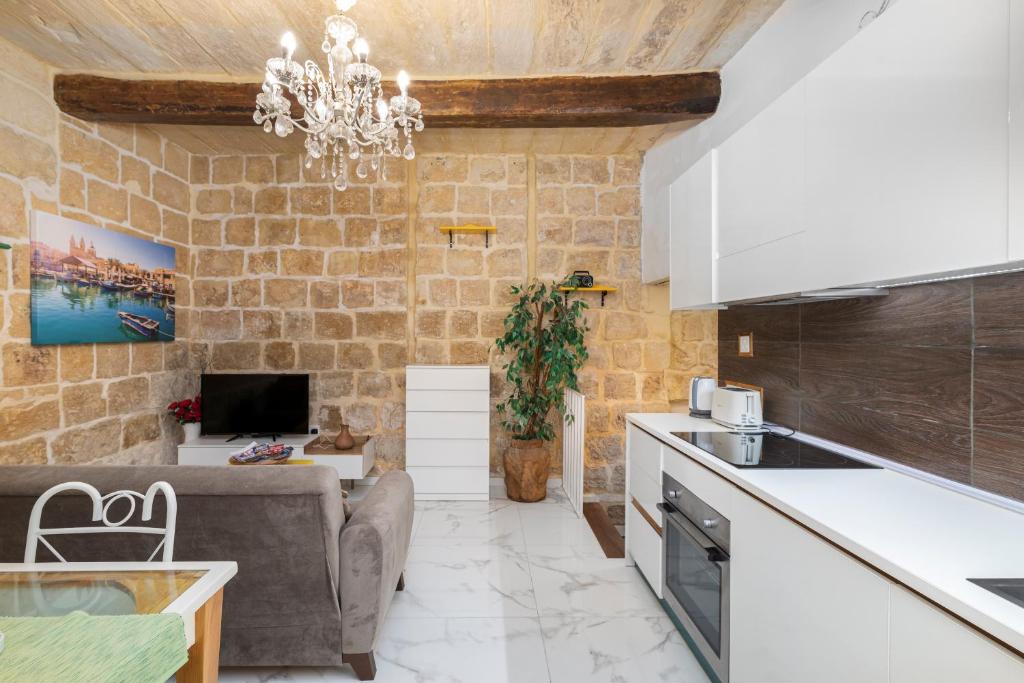 eine Küche und ein Wohnzimmer mit einer Steinmauer in der Unterkunft Chic, Stylish 1 Bedroom Maisonette - Close to Valletta in Floriana