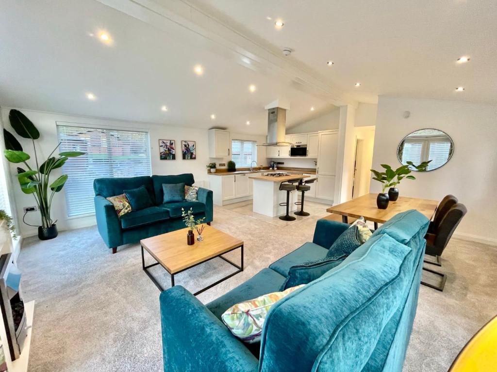 a living room with blue couches and a kitchen at Thirlmere 4 Luxury Lodge at White Cross Bay Windermere in Windermere