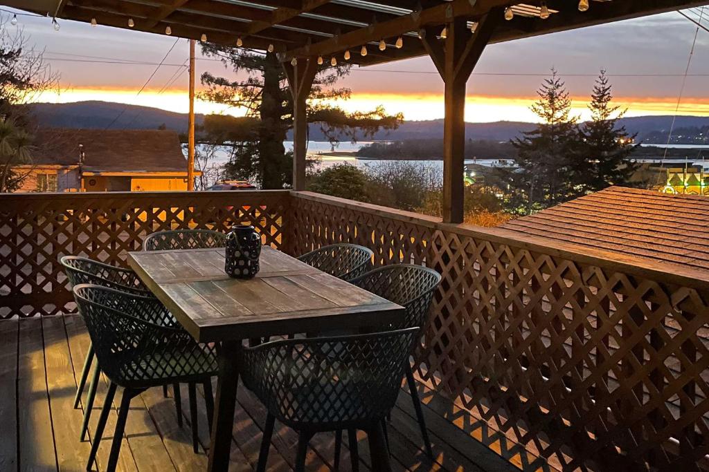 une table et des chaises en bois sur une terrasse avec un coucher de soleil dans l'établissement Pet-Friendly North Bend Home with Bay Views!, à North Bend